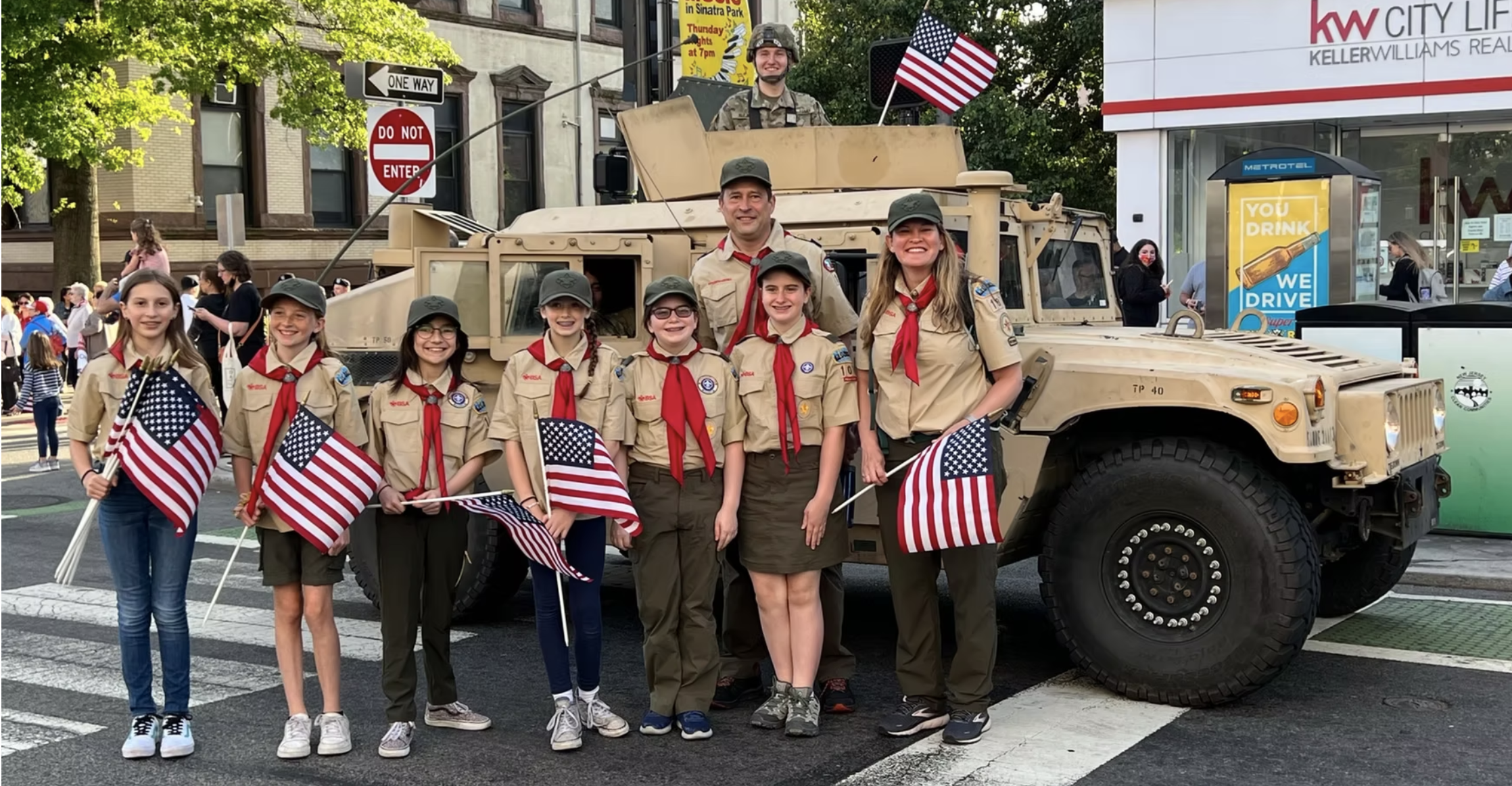 Troop 107G waving flags during a parade, an example of Scouts at an event